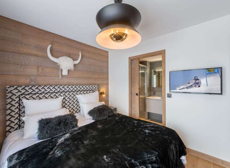 Experience luxury in this stunning bedroom featuring a unique wood-paneled wall and a stylish headboard.