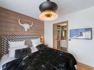 Experience luxury in this stunning bedroom featuring a unique wood-paneled wall and a stylish headboard.