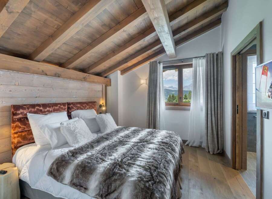 Experience luxury in this stunning bedroom featuring a cozy bed with a plush fur blanket and soft white pillows.