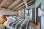 Experience luxury in this stunning bedroom featuring a cozy bed with a plush fur blanket and soft white pillows.