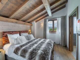 Experience luxury in this stunning bedroom featuring a cozy bed with a plush fur blanket and soft white pillows.