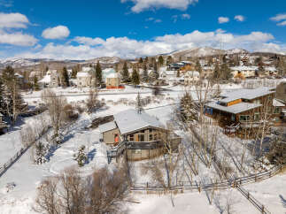 Nestled in a serene winter wonderland, this stunning property boasts a modern design with a snow-covered roof and a welcoming red door.