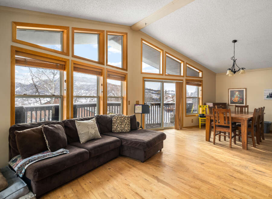 This stunning living space boasts an abundance of natural light, thanks to the expansive windows that frame breathtaking mountain views.