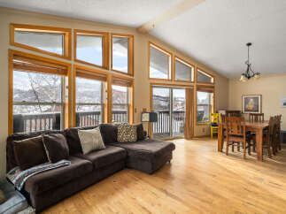 This stunning living space boasts an abundance of natural light, thanks to the expansive windows that frame breathtaking mountain views.