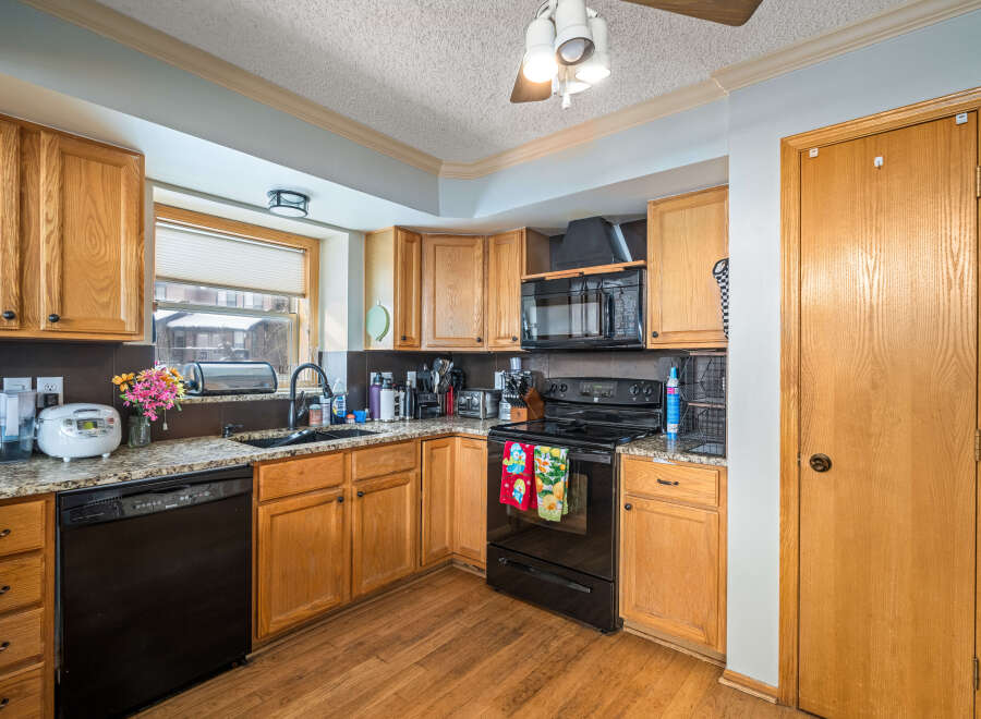This charming kitchen boasts beautiful wooden cabinetry and a sleek black appliance package, creating a warm and inviting atmosphere.