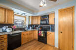 This charming kitchen boasts beautiful wooden cabinetry and a sleek black appliance package, creating a warm and inviting atmosphere.
