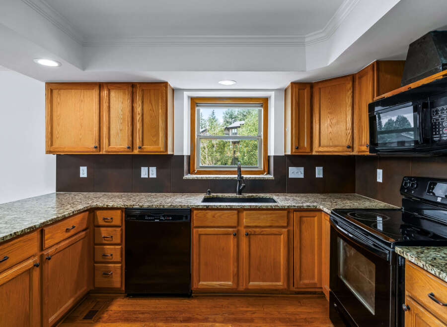 This charming kitchen features warm oak cabinetry complemented by elegant granite countertops.