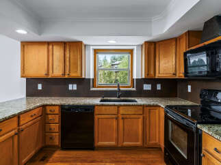 This charming kitchen features warm oak cabinetry complemented by elegant granite countertops.