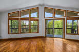 Experience breathtaking views from this stunning living room, featuring a wall of large windows and a sliding glass door that opens to a spacious deck.