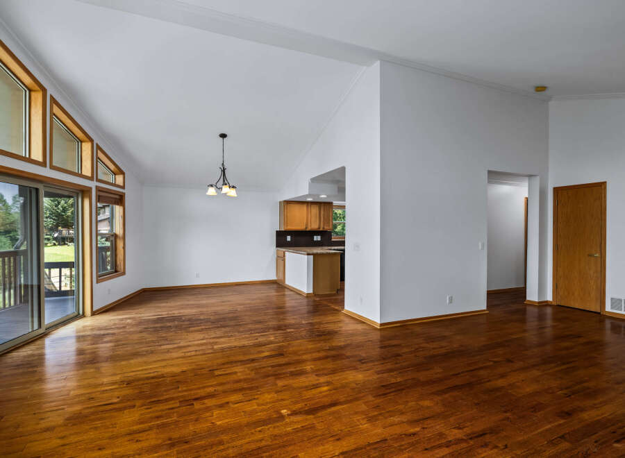 Experience spacious living in this open-concept home featuring a vaulted ceiling and abundant natural light from large windows.
