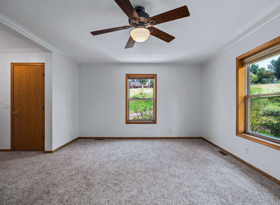 Step into this spacious room, featuring a warm wooden door and a large window offering picturesque views of the outdoors.