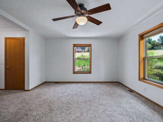 Step into this spacious room, featuring a warm wooden door and a large window offering picturesque views of the outdoors.