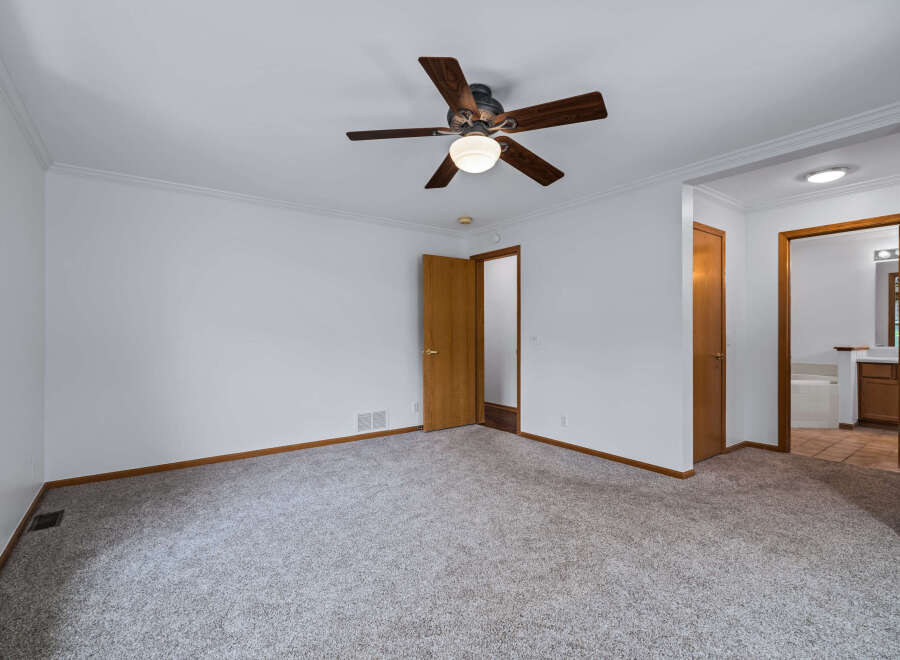 Step into this spacious bedroom featuring a comfortable carpeted floor and a ceiling fan for optimal comfort.