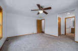 Step into this spacious bedroom featuring a comfortable carpeted floor and a ceiling fan for optimal comfort.