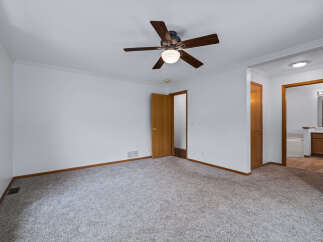 Step into this spacious bedroom featuring a comfortable carpeted floor and a ceiling fan for optimal comfort.