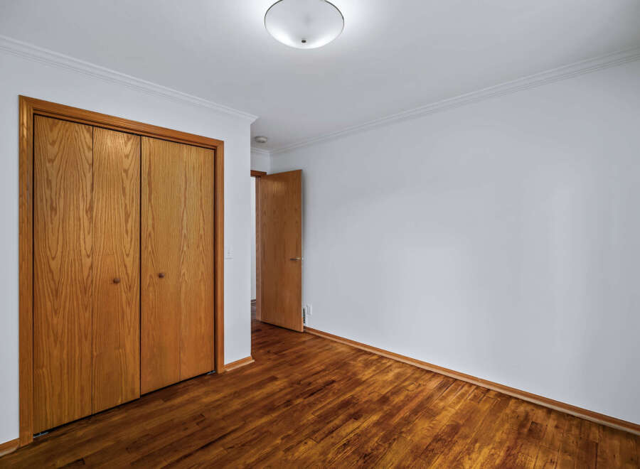 Step into this inviting room featuring a spacious closet with beautiful wooden doors, perfect for ample storage.