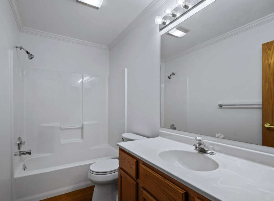 This bright and clean bathroom features a spacious white bathtub and shower combo, perfect for relaxing after a long day.