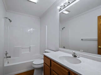 This bright and clean bathroom features a spacious white bathtub and shower combo, perfect for relaxing after a long day.
