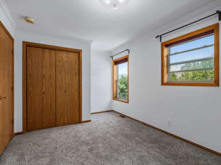 This bedroom features a spacious closet with natural wood doors and a matching interior door.