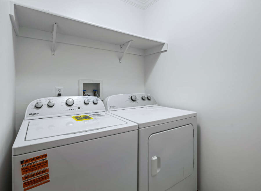 This laundry room features a white Whirlpool top-load washing machine and a matching dryer.