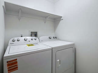This laundry room features a white Whirlpool top-load washing machine and a matching dryer.