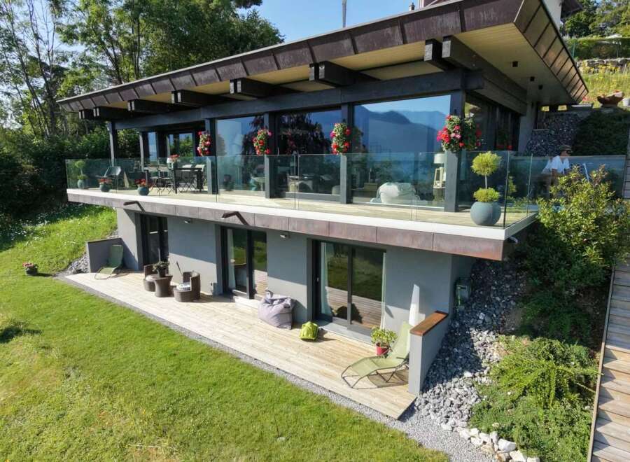 Experience modern luxury in this stunning hillside home, featuring expansive glass walls that offer breathtaking mountain and lake views.