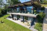 Experience modern luxury in this stunning hillside home, featuring expansive glass walls that offer breathtaking mountain and lake views.