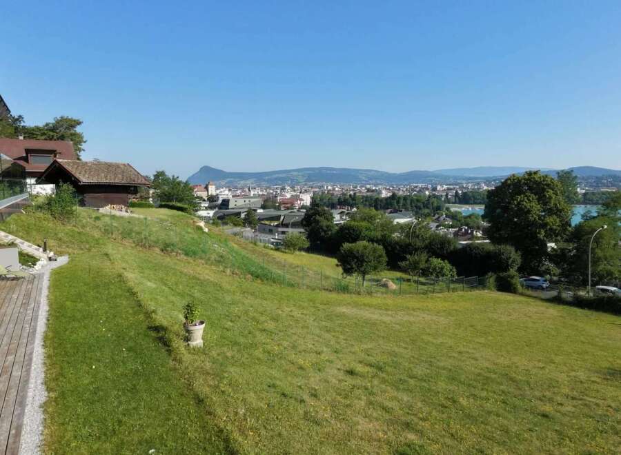 Experience breathtaking panoramic views from this stunning property, featuring a modern home with expansive glass railings and a spacious wooden deck perfect for entertaining.