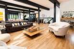 Experience modern living in this spacious open-concept home featuring a sleek dark kitchen and a comfortable living area with a rich leather sofa.