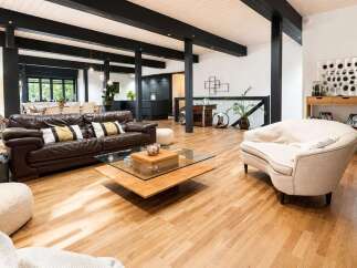 Experience modern living in this spacious open-concept home featuring a sleek dark kitchen and a comfortable living area with a rich leather sofa.