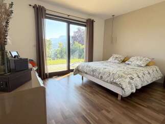 Experience breathtaking mountain and lake views from this serene bedroom, featuring a comfortable queen-size bed with a nature-inspired duvet.