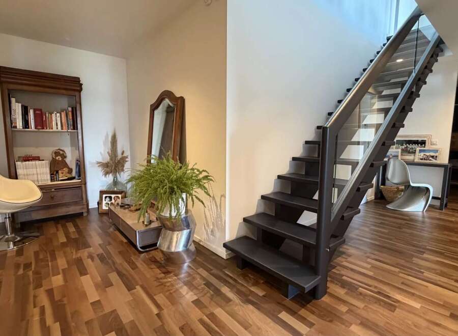 Experience modern living with this stunning staircase featuring sleek glass railings and dark wood treads, seamlessly connecting to a beautifully appointed entryway.