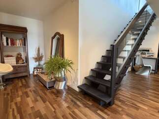 Experience modern living with this stunning staircase featuring sleek glass railings and dark wood treads, seamlessly connecting to a beautifully appointed entryway.