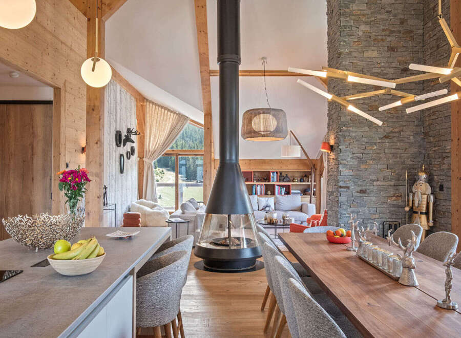 Experience luxurious mountain living in this stunning open-concept living space, featuring a dramatic suspended fireplace and a modern chandelier.