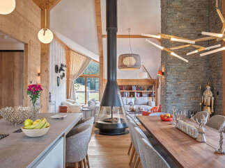Experience luxurious mountain living in this stunning open-concept living space, featuring a dramatic suspended fireplace and a modern chandelier.