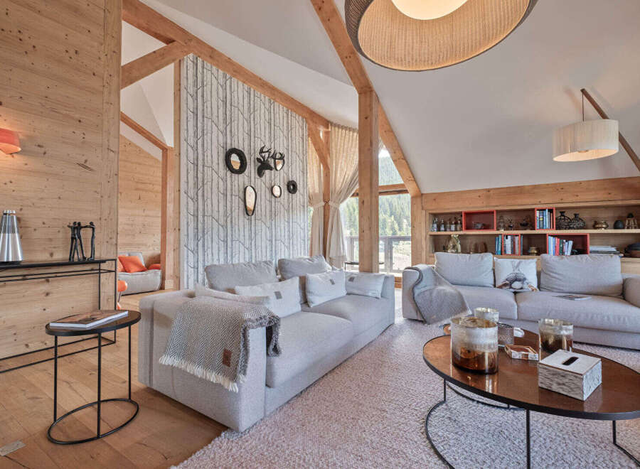 Experience luxurious mountain living in this stunning chalet, featuring a spacious living area with exposed wooden beams and a cozy fireplace.