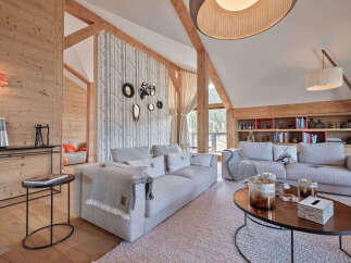 Experience luxurious mountain living in this stunning chalet, featuring a spacious living area with exposed wooden beams and a cozy fireplace.