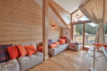 Experience luxurious mountain living in this stunning chalet-style living room, featuring warm wood paneling and a cozy sectional sofa adorned with vibrant orange and plaid cushions.