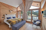 Experience luxurious mountain living in this stunning bedroom, featuring a cozy bed adorned with a plaid throw and a plush bench.