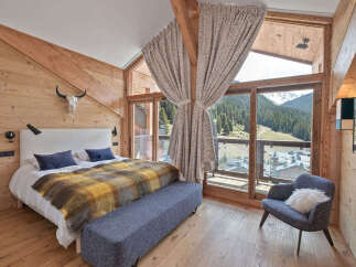 Experience luxurious mountain living in this stunning bedroom, featuring a cozy bed adorned with a plaid throw and a plush bench.