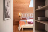 Experience cozy mountain living in this charming bedroom featuring warm wood paneling and a comfortable bed adorned with a vibrant, textured throw.