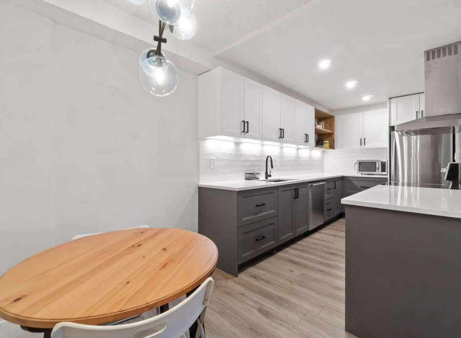 This modern kitchen boasts a sleek design with white cabinetry and contrasting gray lower cabinets.