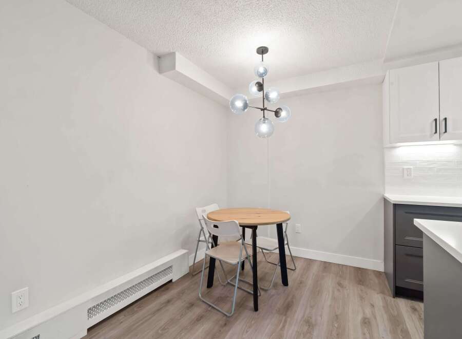 This charming dining area features a modern light fixture and a round wooden table, perfect for intimate meals.