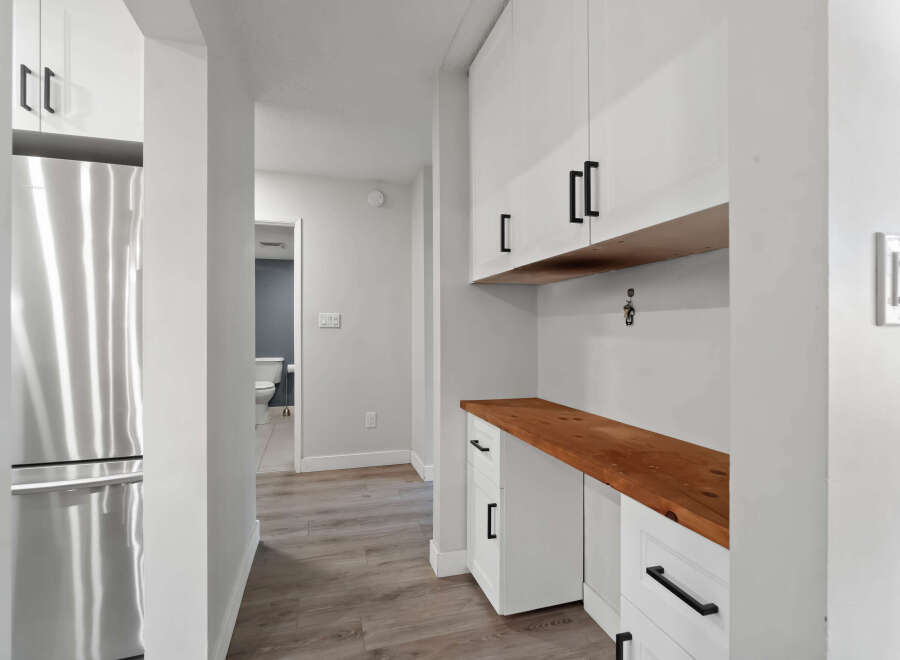 Step into this beautifully designed home and discover a modern kitchen with sleek white cabinetry and a warm wooden countertop.
