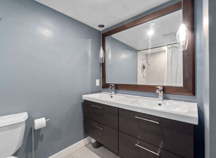 This modern bathroom features a sleek double vanity with ample storage, perfect for a shared space.