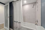 Step into this modern bathroom featuring a sleek shower and a pristine white bathtub.