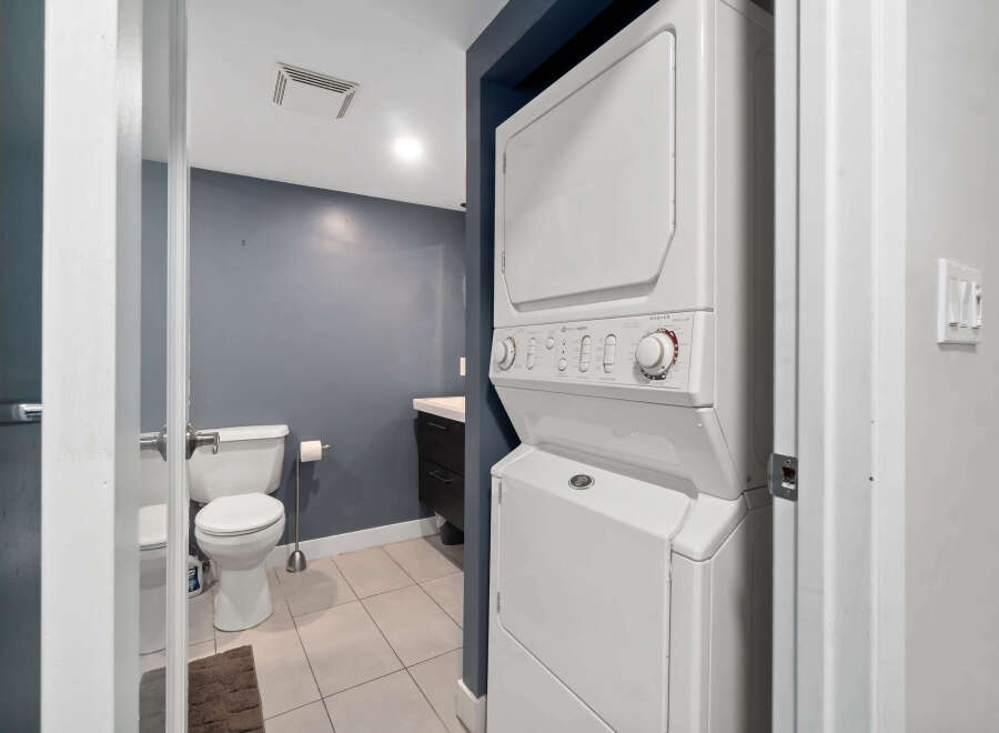Step into this well-maintained bathroom featuring a convenient stacked washer and dryer, perfect for modern living.