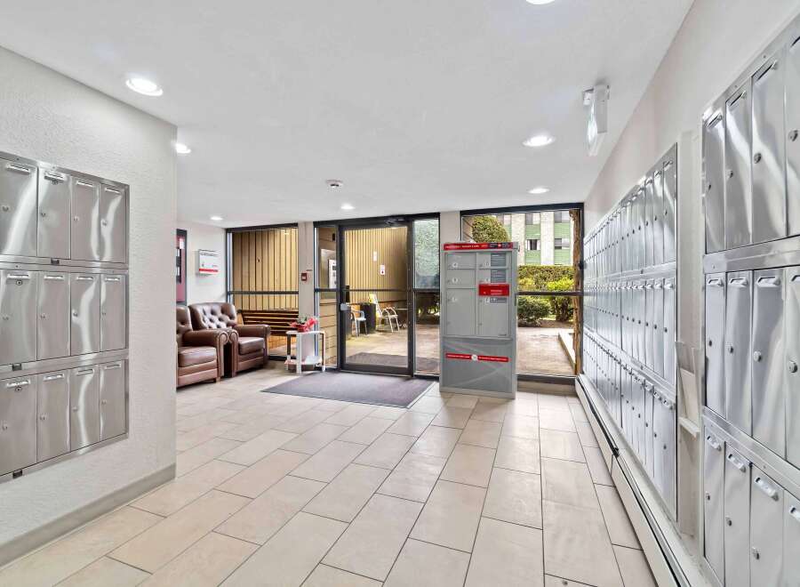 This inviting apartment building entrance features a well-lit hallway with modern mailboxes.