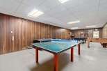This recreational space features a variety of entertainment options, including a ping pong table, pool table, and foosball table.