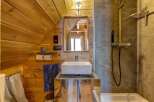 This charming bathroom features a unique wooden sloped ceiling, creating a cozy and inviting atmosphere.